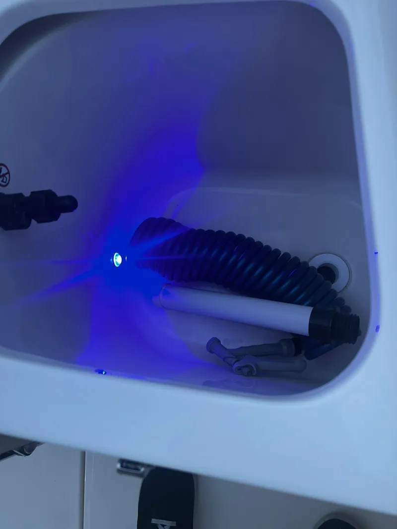 Slide: The Image of 2024 Scout 215 XSF boat compartment with blue LED lighting and coiled hose. - 10