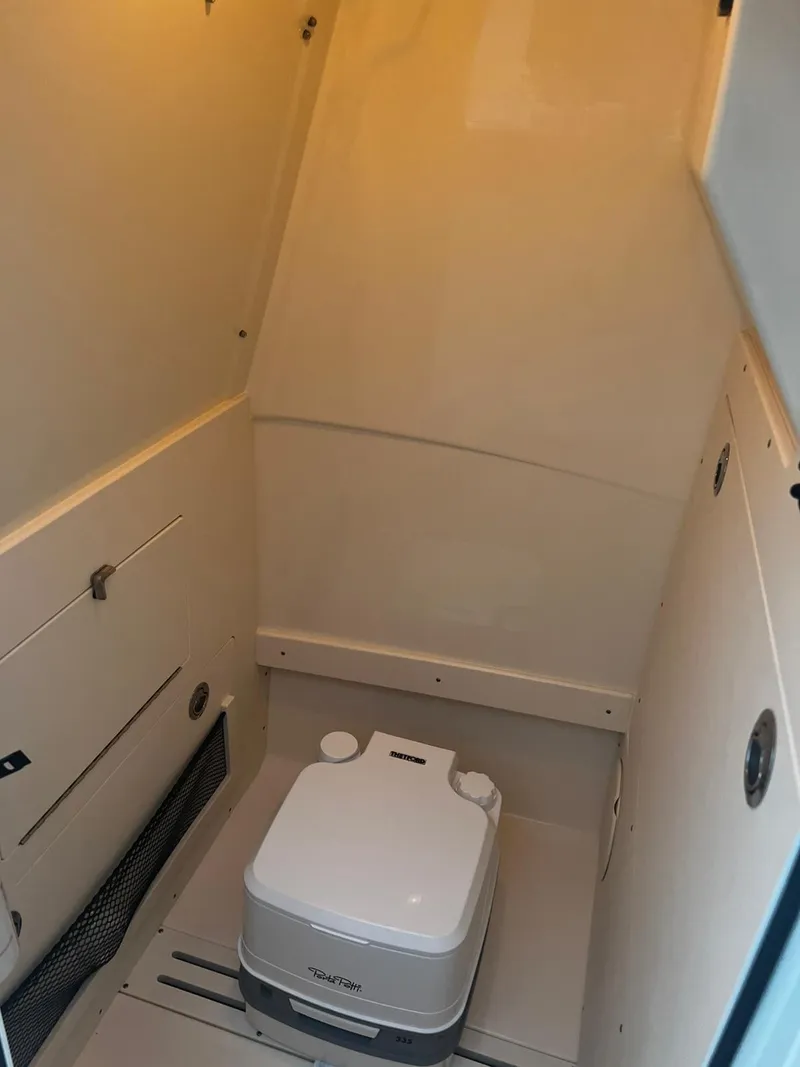 Slide: The Image of 2024 Scout 215 XSF boat interior with compact portable toilet. - 11