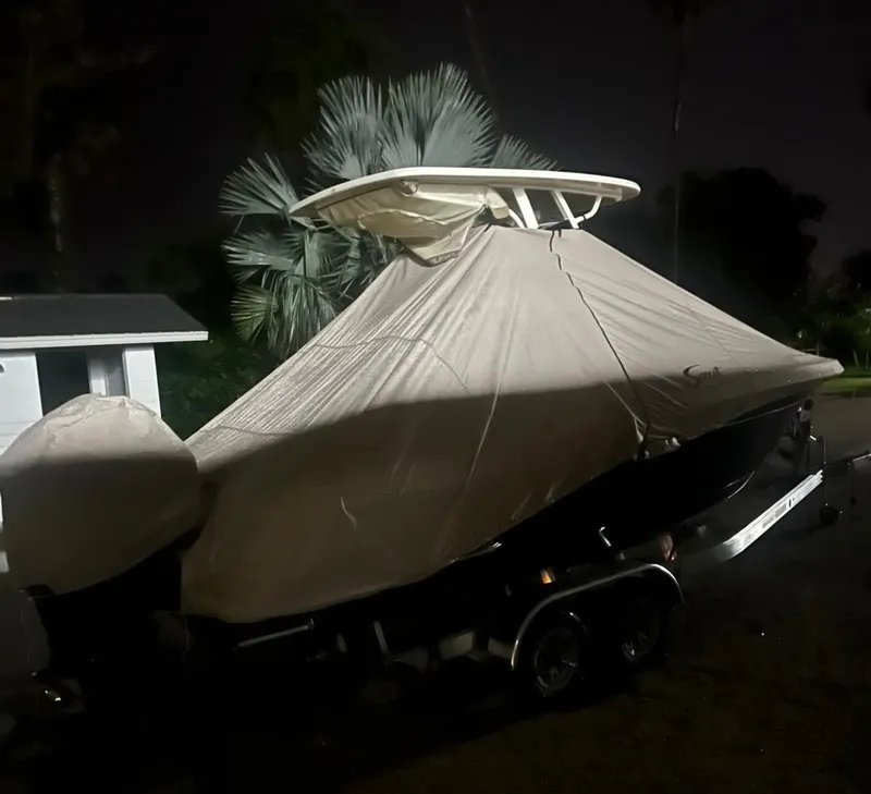 Slide: The Image of 2024 Scout 215 XSF boat covered, parked on trailer at night. - 12