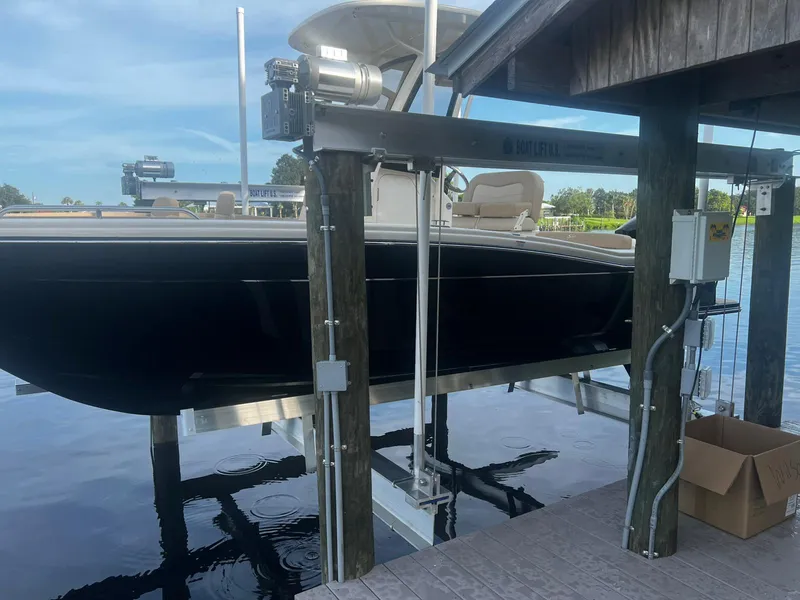 Slide: The Image of 2024 Scout 215 XSF boat on lift at dockside, under a clear blue sky. - 3