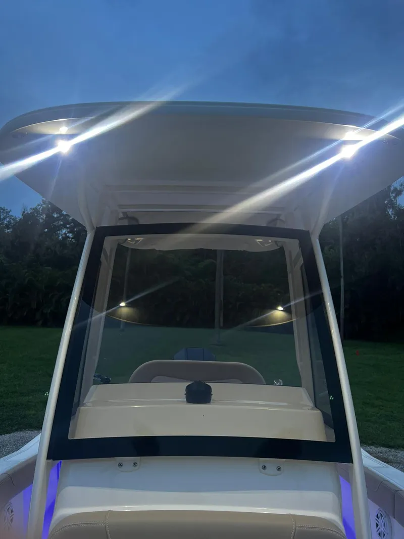 Slide: The Image of 2024 Scout 215 XSF boat with illuminated canopy at dusk. - 9