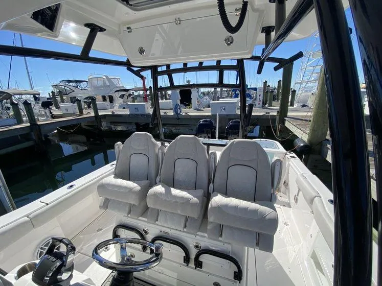 Slide: The Image of 2022 Sea Fox 328 Commander boat interior with three cushioned seats at a marina. - 18
