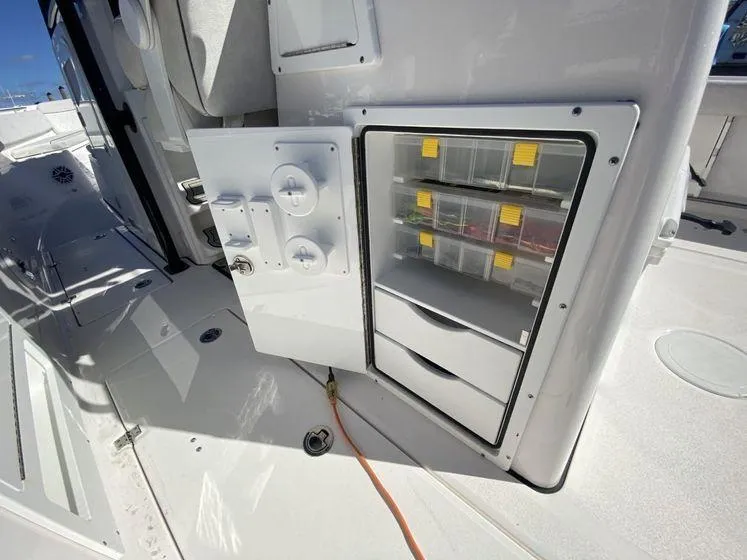 Slide: The Image of 2022 Sea Fox 328 Commander storage compartment with organized tackle boxes and drawers. - 35