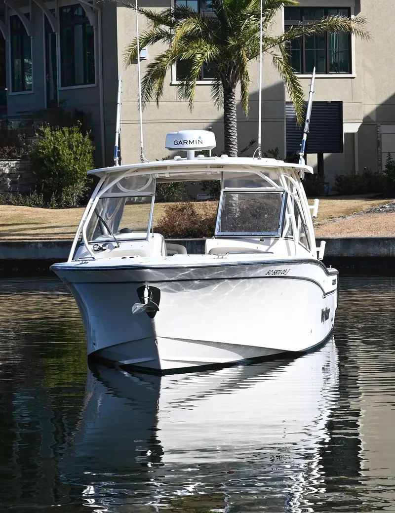 Slide: The Image of 2014 Grady-White Freedom 307 boat docked near a waterfront building. - 10