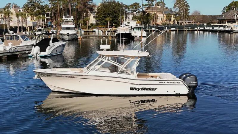 Slide: The Image of 2014 Grady-White Freedom 307 boat docked in a marina, reflecting on calm water. - 13