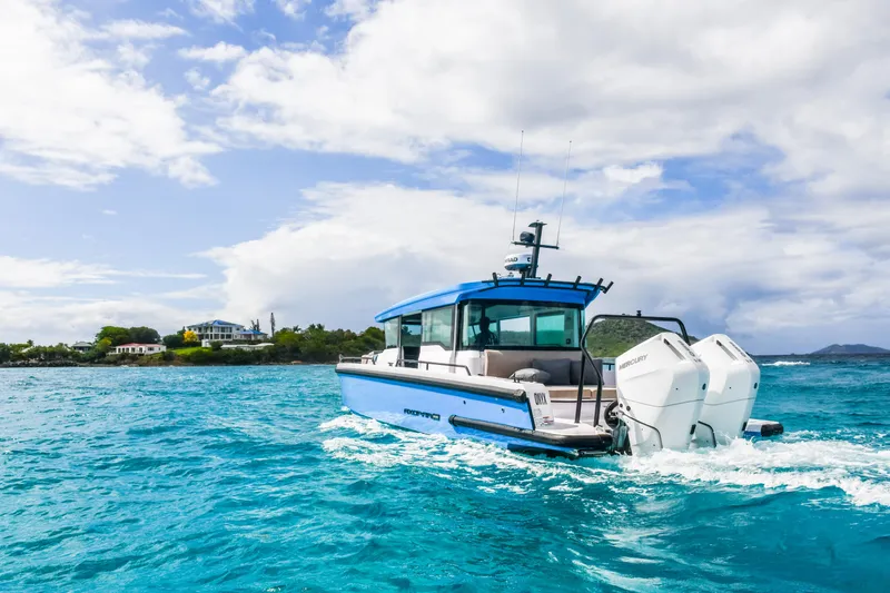 Slide: The Image of 2024 Axopar 37 Cross Cabin boat cruising on clear blue water under a partly cloudy sky. - 5