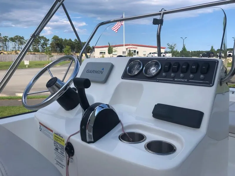 Slide: The Image of 2024 Boston Whaler 190 Montauk console with Garmin navigation, steering wheel, and controls. - 2