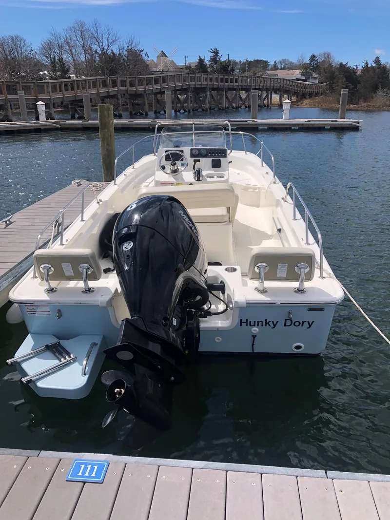 Slide: The Image of 2024 Boston Whaler 190 Montauk boat docked, featuring a powerful outboard motor. - 6