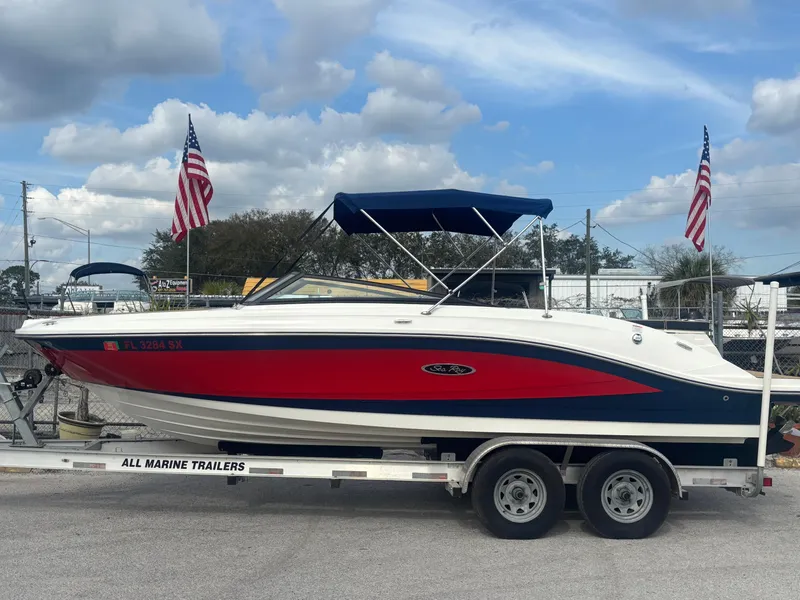 Slide: The Image of 2021 Sea Ray SPX 230 boat on trailer with American flags in background. - 0