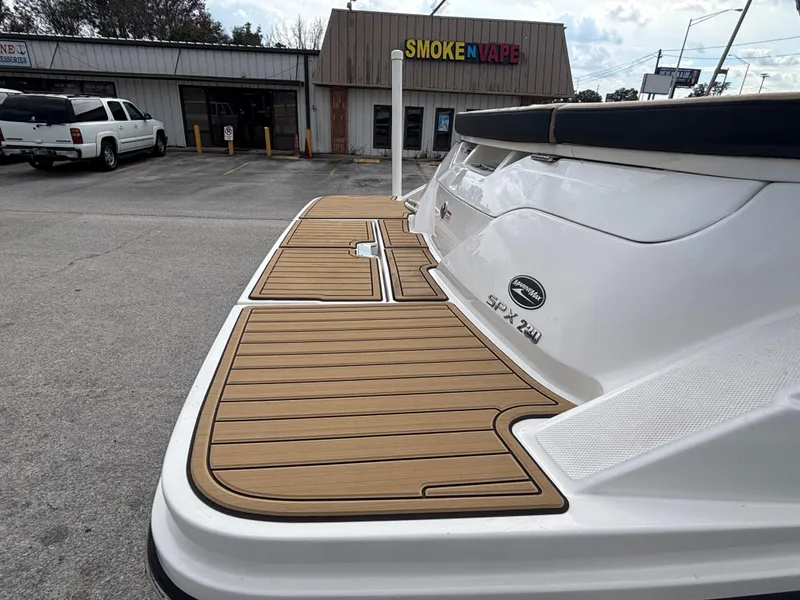 Slide: The Image of 2021 Sea Ray SPX 230 boat with teak-style swim platform in parking lot. - 12