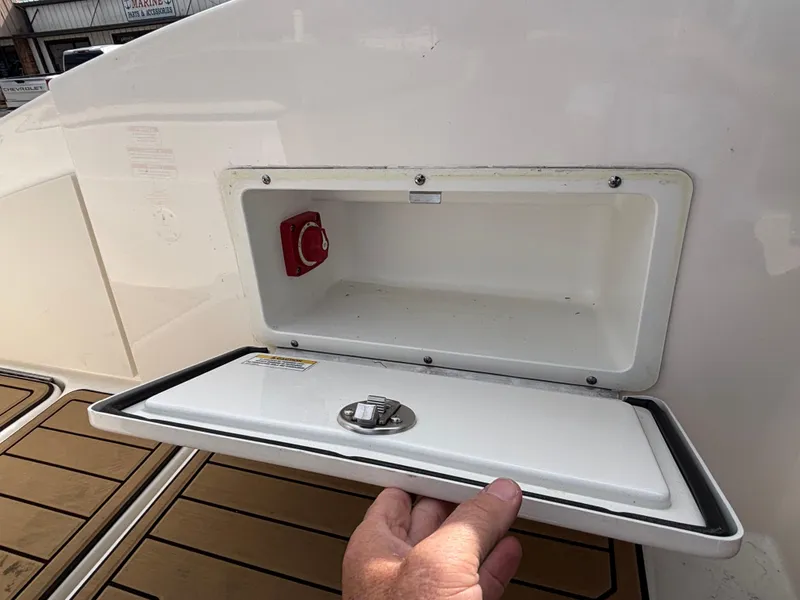 Slide: The Image of 2021 Sea Ray SPX 230 boat storage compartment with open hatch and visible red switch. - 28