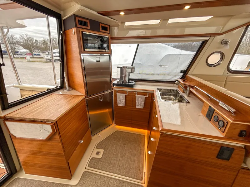 Slide: The Image of Interior of 2023 Ranger Tugs R-43 CB yacht, featuring modern kitchen with wood cabinetry and stainless appliances. - 15