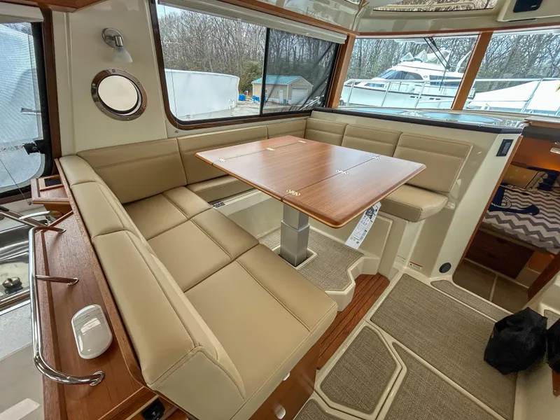 Slide: The Image of 2023 Ranger Tugs R-43 CB interior with beige seating and wooden table. - 16