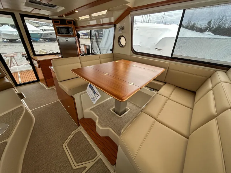 Slide: The Image of 2023 Ranger Tugs R-43 CB interior with beige seating and wooden table, showcasing modern design. - 17