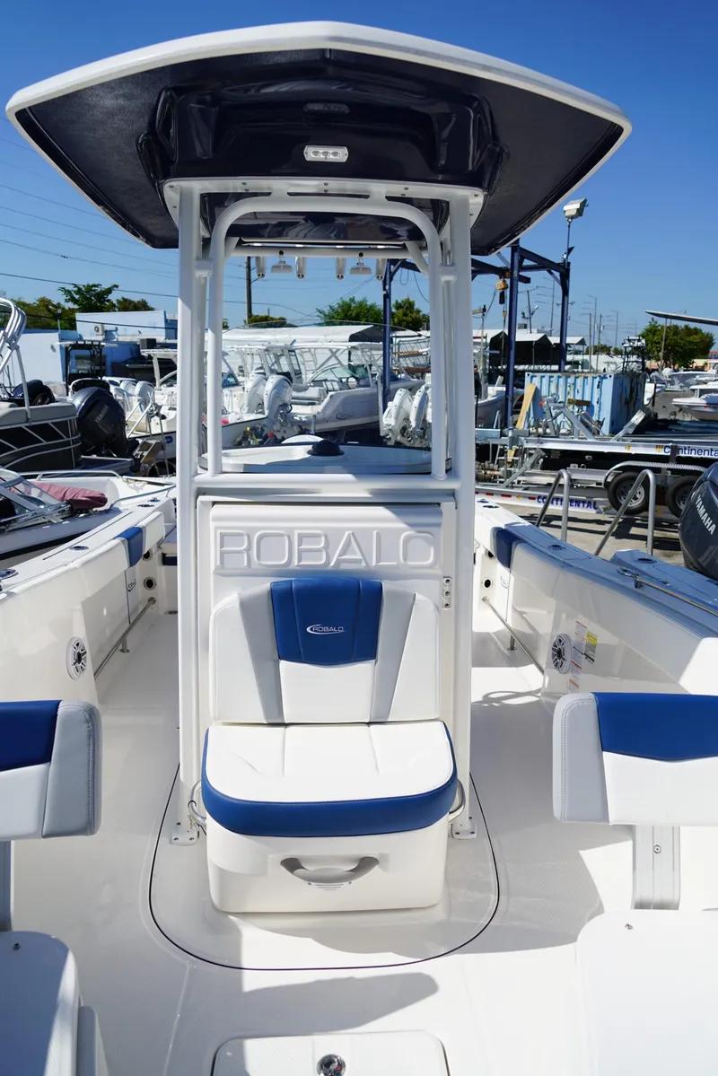 Slide: The Image of 2025 Robalo R232 EX boat interior with blue and white seating, center console, and T-top. - 12