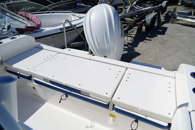 Slide: The Image of 2025 Robalo R232 EX boat deck with seating and motor, in a marina setting. - 15