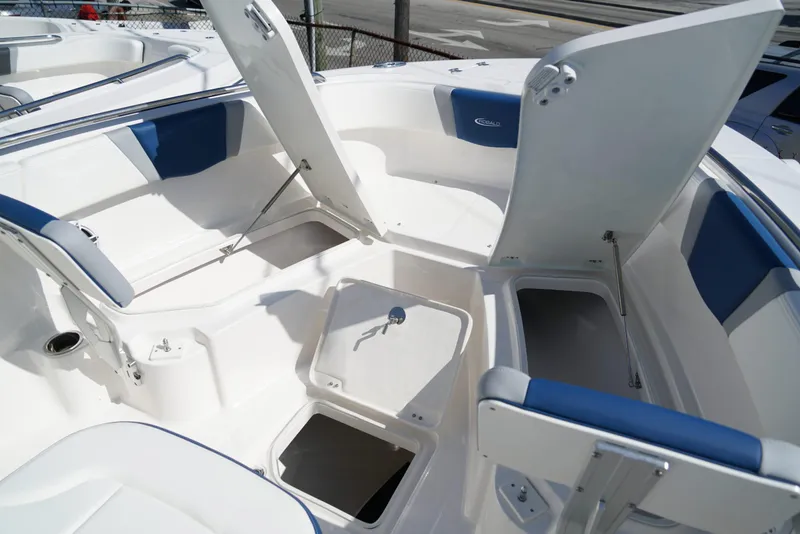 Slide: The Image of 2025 Robalo R232 EX boat interior with open storage compartments and blue seating. - 23