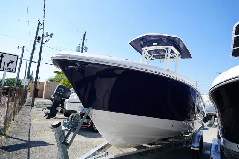 Slide: The Image of 2025 Robalo R232 EX boat on trailer, parked outdoors under clear blue sky. - 3