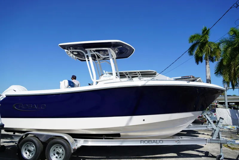 Slide: The Image of 2025 Robalo R232 EX boat on trailer under clear blue sky. - 4