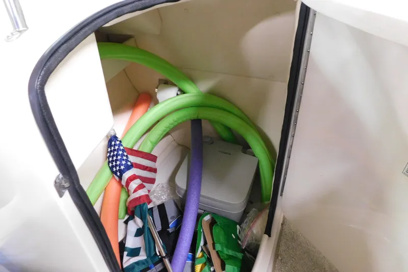 Slide: The Image of Storage compartment in 2007 Sea Ray 220 Sundeck with pool noodles and American flag. - 12