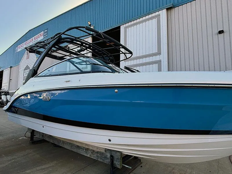 Slide: The Image of 2025 Sea Ray SLX 260 Outboard boat, blue and white, docked near a marina building. - 4