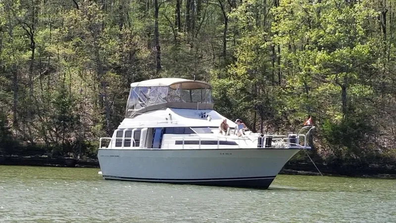 Slide: The Image of 1989 Mainship 41 Grand Salon yacht anchored on a serene lake with forested background. - 1