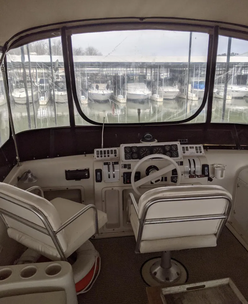 Slide: The Image of 1989 Mainship 41 Grand Salon helm with marina view, featuring dual captain chairs and control panel. - 26