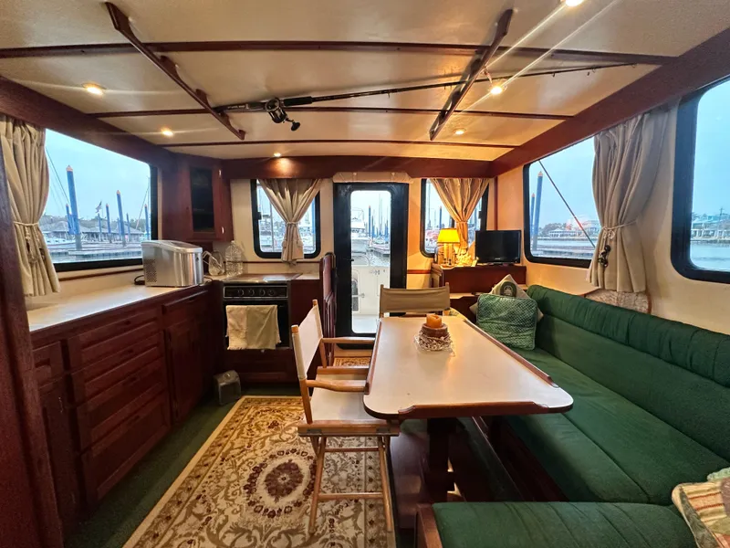 Slide: The Image of Interior of 2001 Nordic Tug 37, featuring cozy seating and dining area with marina view. - 18
