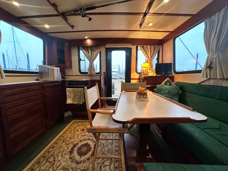 Slide: The Image of Interior of 2001 Nordic Tug 37, featuring cozy seating and dining area with nautical decor. - 23