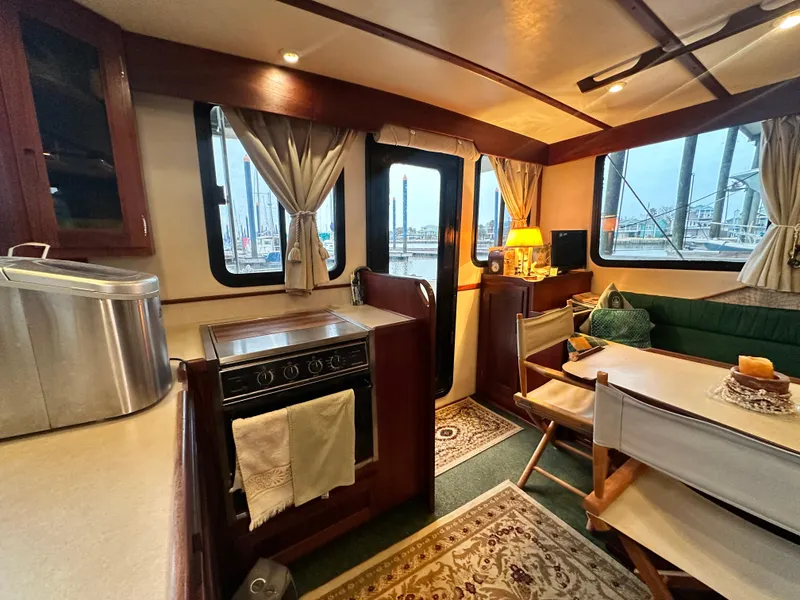 Slide: The Image of Interior of a 2001 Nordic Tug 37, featuring a cozy dining area and kitchen. - 25