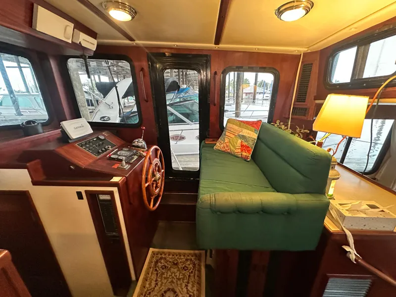 Slide: The Image of Cozy interior of a 2001 Nordic Tug 37 with helm, green sofa, and nautical decor. - 32
