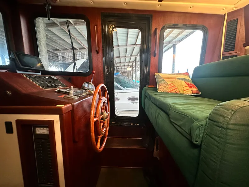 Slide: The Image of Interior of a 2001 Nordic Tug 37, featuring helm and green seating. - 33