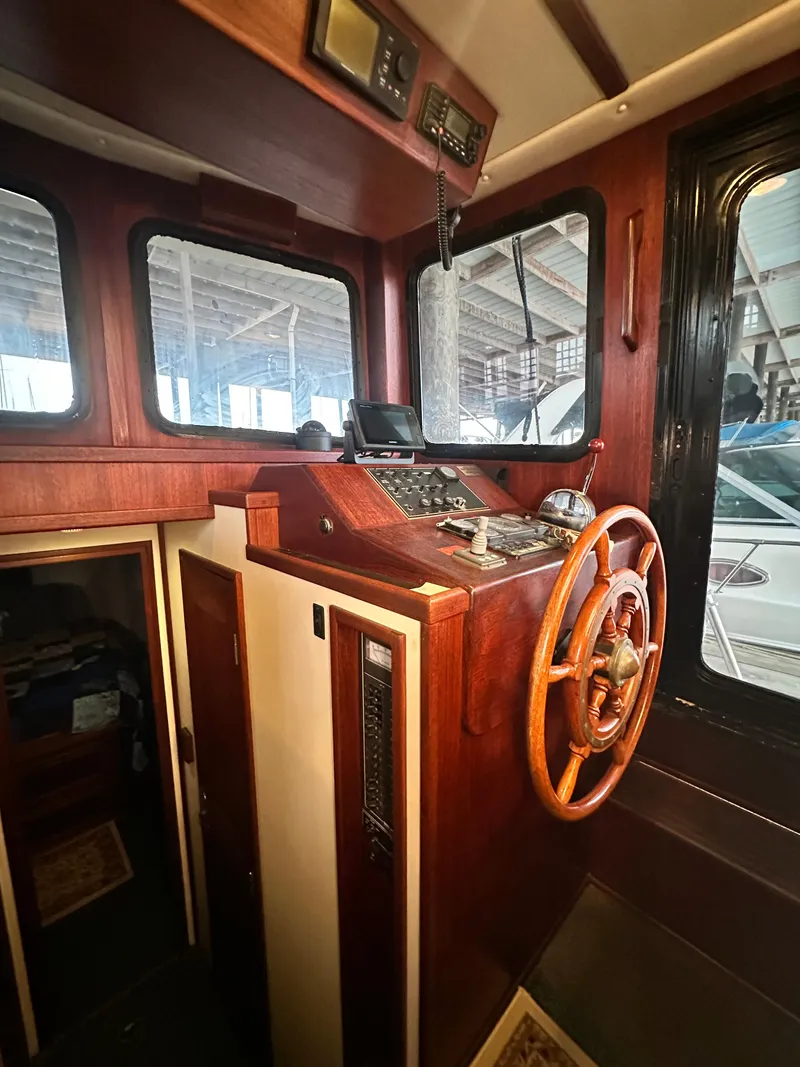 Slide: The Image of Interior helm of 2001 Nordic Tug 37 with wooden steering wheel and navigation equipment. - 37
