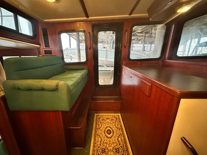 Slide: The Image of Interior of 2001 Nordic Tug 37 with green seating and wooden cabinetry. - 38