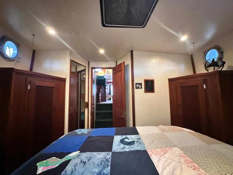 Slide: The Image of Interior cabin of a 2001 Nordic Tug 37 with quilted bedspread and wooden cabinetry. - 50