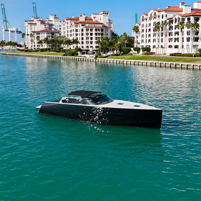 Slide: The Image of 2014 VanDutch 55 yacht cruising in turquoise waters near luxury waterfront buildings. - 2