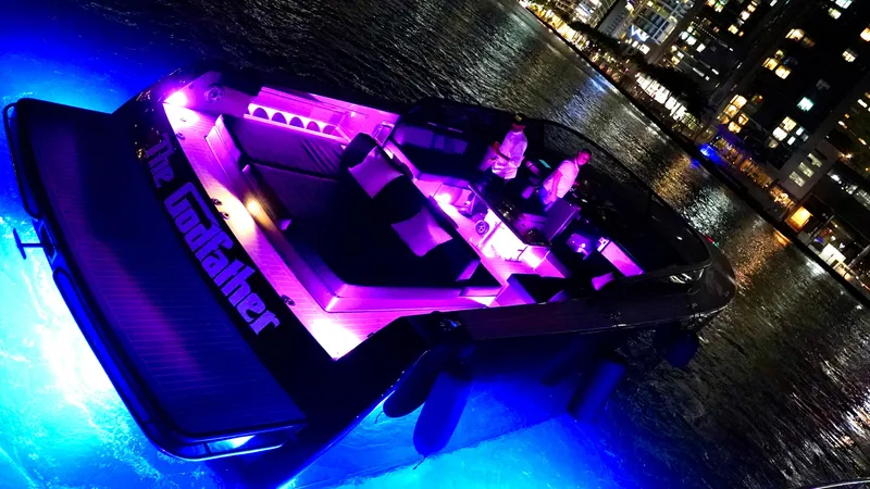 Slide: The Image of VanDutch 55 yacht, 2014 model, illuminated with vibrant purple and blue lights on water. - 44