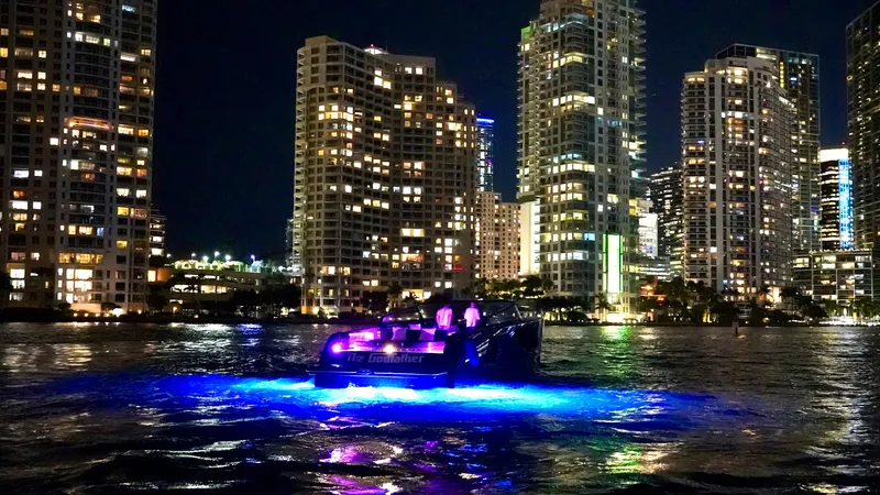 Slide: The Image of VanDutch 55 yacht illuminated on water at night, city skyline in background. - 46
