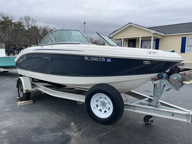 Slide: The Image of 2014 Chaparral 19 Sport H2O boat on trailer, parked outdoors near a building. - 2