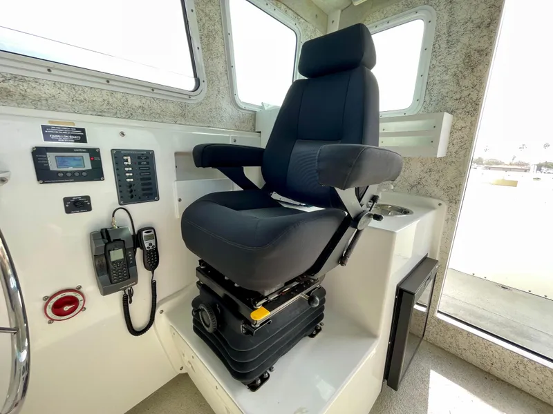 Slide: The Image of Captain's chair in 2012 Farallon 2800 Whaleback boat cockpit, featuring control panel and communication devices. - 12