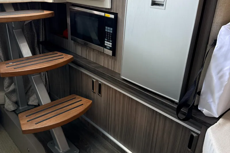 Slide: The Image of Interior of 2020 Sea Ray 32 Sundancer Outboard with microwave, fridge, and wooden steps. - 11