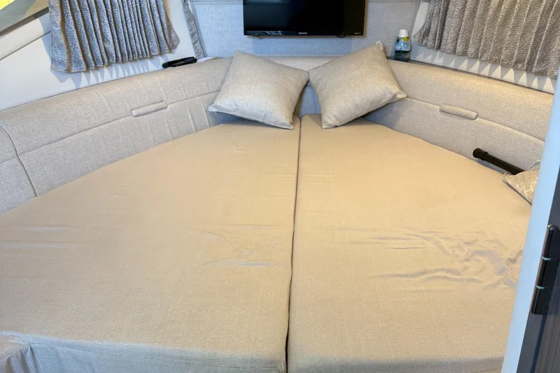 Slide: The Image of Interior cabin of 2020 Sea Ray 32 Sundancer Outboard with beige bedding and pillows. - 9