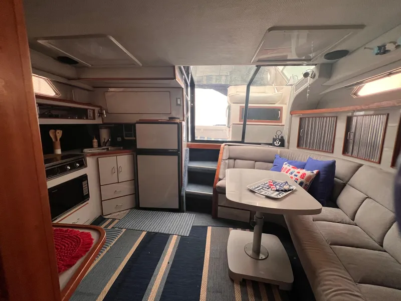 Slide: The Image of 1989 Sea Ray 390 Express Cruiser interior with seating, table, and nautical decor. - 28
