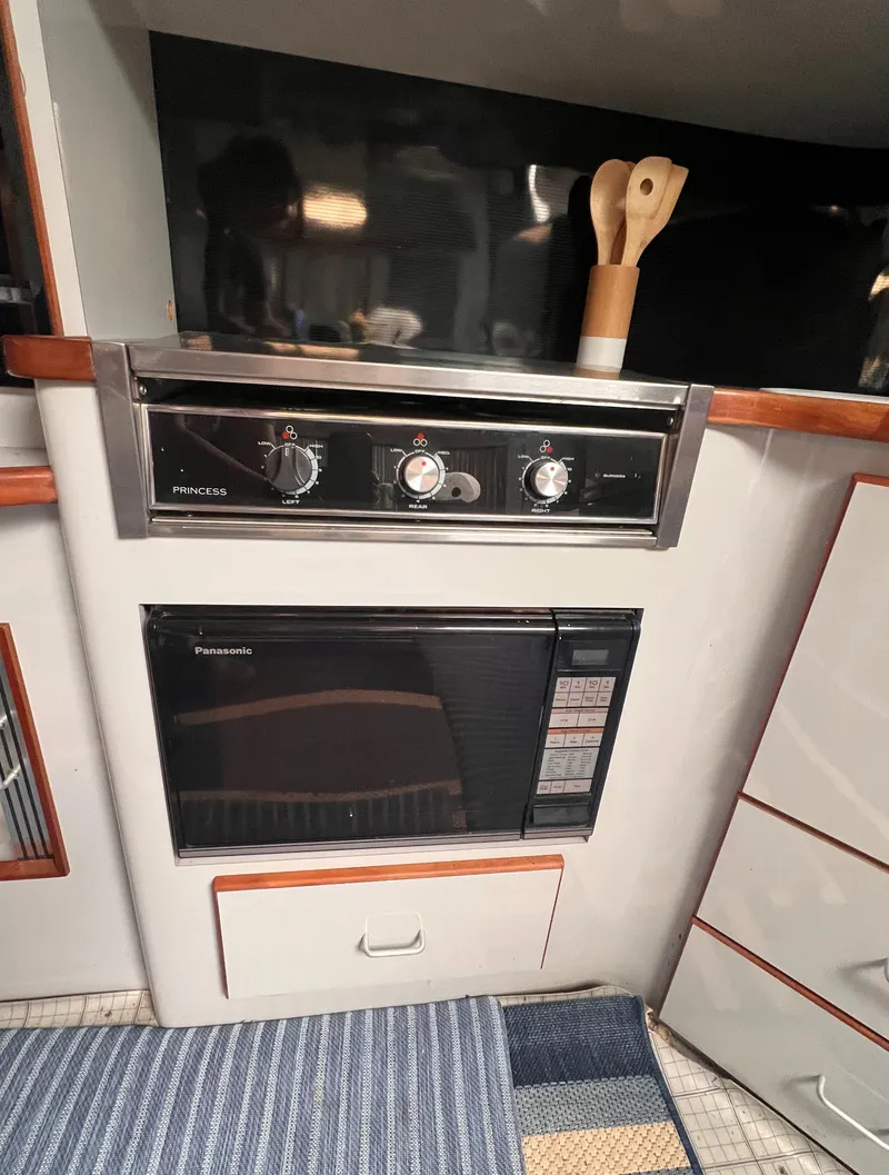 Slide: The Image of 1989 Sea Ray 390 Express Cruiser interior with kitchen, seating area, and striped rug. - 29
