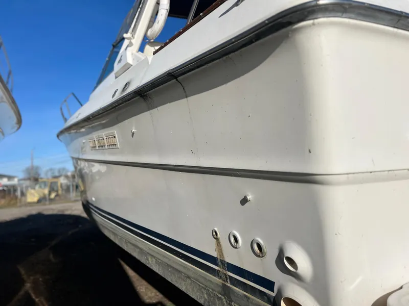 Slide: The Image of 1989 Sea Ray 390 Express Cruiser on land, surrounded by boats and construction equipment. - 40