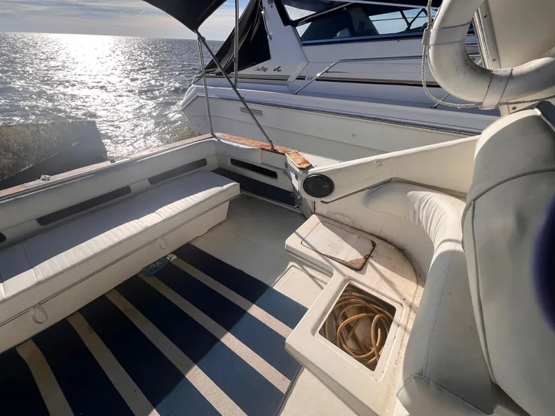 Slide: The Image of 1989 Sea Ray 390 Express Cruiser with spacious seating and canopy, docked under clear skies. - 5