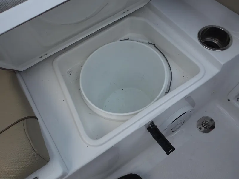 Slide: The Image of 2016 Sea Hunt Escape 235 SE boat storage compartment with bucket and cup holder. - 26