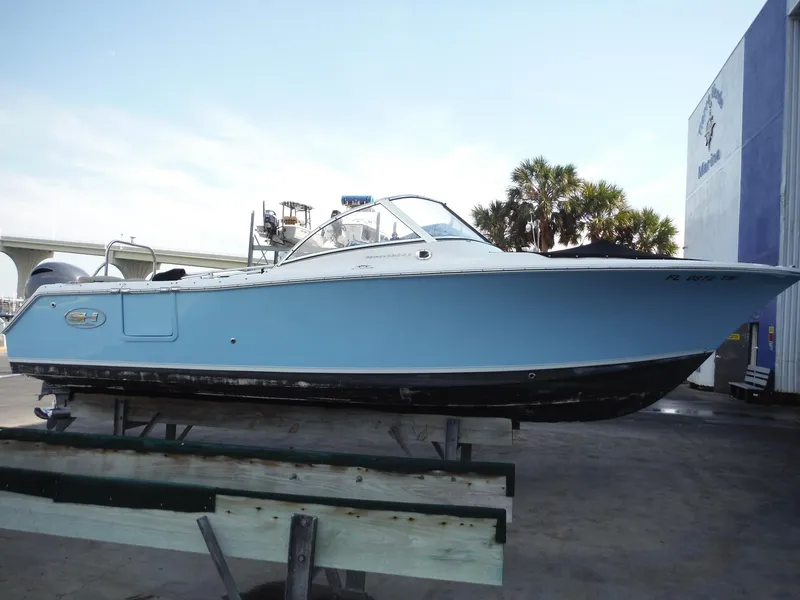 Slide: The Image of 2016 Sea Hunt Escape 235 SE boat on display, light blue hull, parked outdoors. - 33