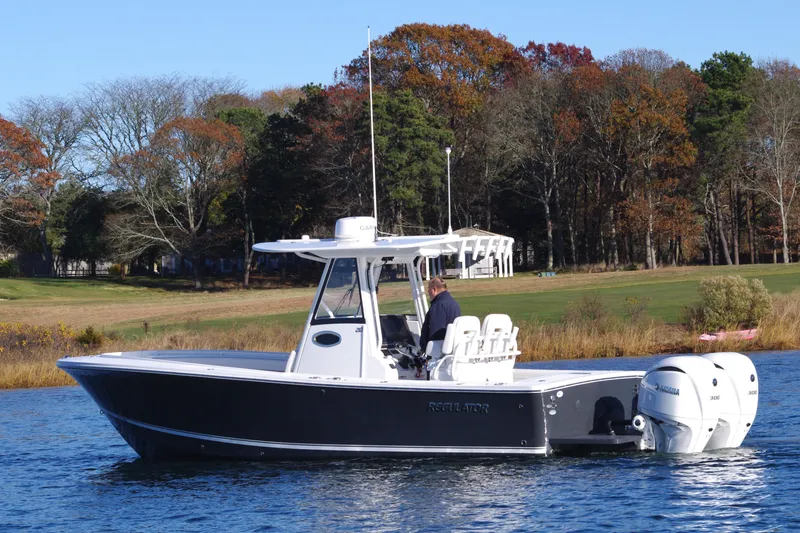 Slide: The Image of 2023 Regulator 28 boat on water, surrounded by autumn trees. - 2