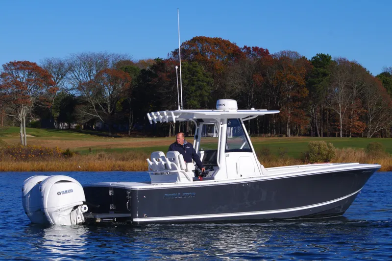 Slide: The Image of 2023 Regulator 28 boat on a calm lake with autumn trees in the background. - 7